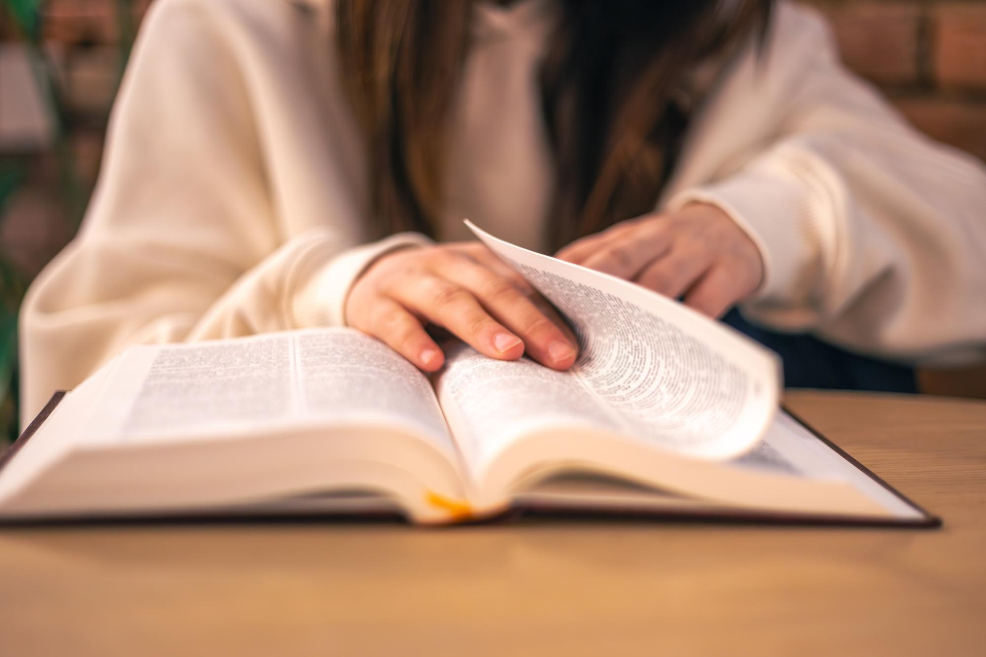 Person reading an open Bible at a table